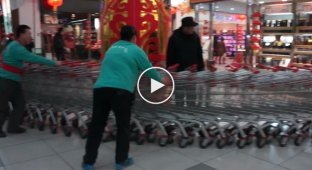Сотрудники китайского супермаркета поднимают тележки на эскалаторе