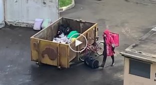 Доставщик еды роется в мусорном баке в Санкт-Петербурге