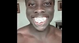 Темнокожий парень демонстрирует белизну своих зубов 
