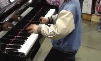 Одаренный ребенок играет на рояле в магазине