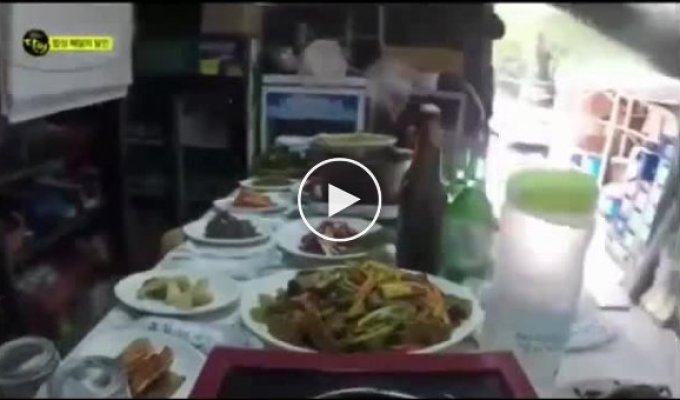 Корейский официант носит на голове обеденный стол заставленный блюдами