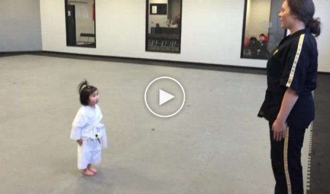 Трехлетняя девочка повторяет слова и движения своего тренера по тхэквондо