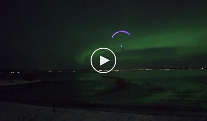 Захватывающий ночной полет на параплане на фоне зеленых волн северного сияния