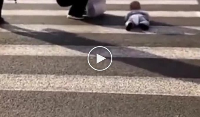 Яжемать фотографирует ребенка, ползающего по пешеходному переходу, посреди оживленной трассы