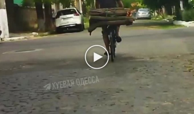 Мужик едет на велосипеде по Одессе с привязанными горящими дровами