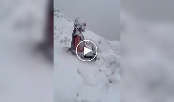 Монах медитирует в горах во время снегопада