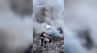 Мужчина и женщина, обнявшись, смотрят, как догорает их дом после прилета российской ракеты в Харькове