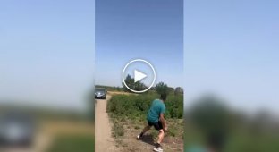A Russian resident is trying to hit a drone flying low over the ground with a stone