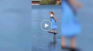 Athlete in Bavarian dress flies over a lake on a hydrofoil