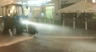 Трактор моет улицы Москвы во время дождя 