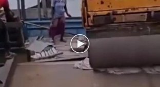 Workers sank a road roller while moving it onto a ship.