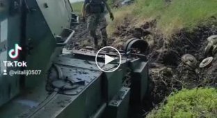 A Ukrainian soldier clears mines from a wrecked Leopard 2A6 tank for further evacuation
