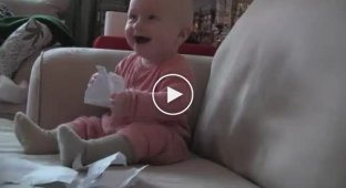 Ребенок смеется от порванной бумаги
