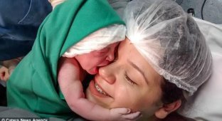 Newborn baby hugs mother's face