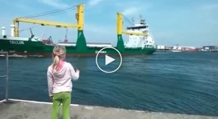 A little girl standing on the pier asks to honk a passing ship.