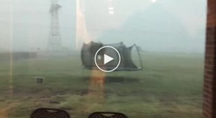 A man tries to save a trampoline during a storm