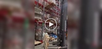 Работник склада аккуратно выровнял неустойчивый стеллаж с помощью погрузчика