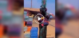 В Африці жінка вразила силою і спритністю, забравши 8 упаковок напоїв — 4 на голові і 4 в руках.