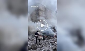 Мужчина и женщина, обнявшись, смотрят, как догорает их дом после прилета российской ракеты в Харькове
