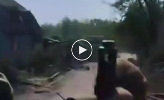 Ukrainian soldiers drive through a village destroyed by artillery shelling