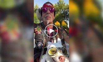 An American biker rides through cities with his dog and parrots