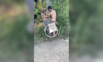 Російський солдат б'є палицею двох своїх соратників, прив'язаних до стовпа