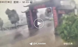 A Chinese moped rider miraculously escaped when a historic gate collapsed onto the road