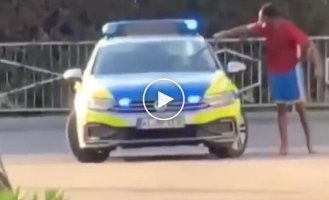 Migrant smashes police car in front of officer and calmly goes about his business
