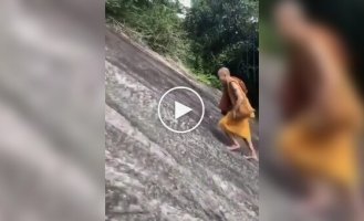 A monk climbs a steep slope without a safety net