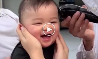 Adorable little boy can't stop giggling while getting his hair cut