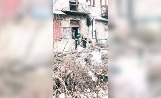 Three occupiers carry a washing machine along the street of occupied and destroyed Avdiivka