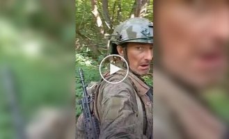 An occupier films his one-legged comrade crawling on all fours through the forest