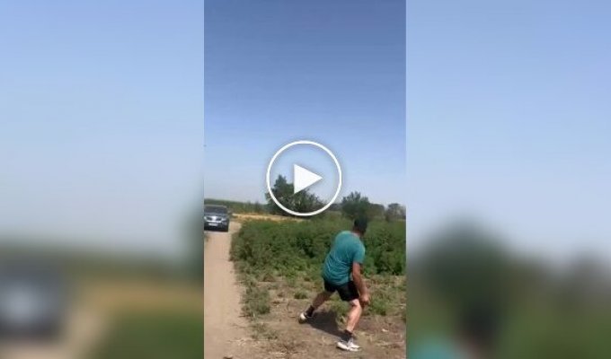 A Russian resident is trying to hit a drone flying low over the ground with a stone