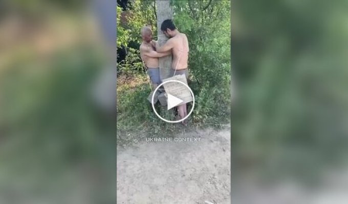 Российский солдат бьет палкой двух своих соратников, привязанных к столбу