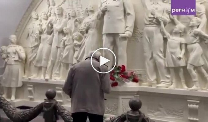 An elderly Russian man crosses himself and bows before a monument to Stalin in the Moscow metro