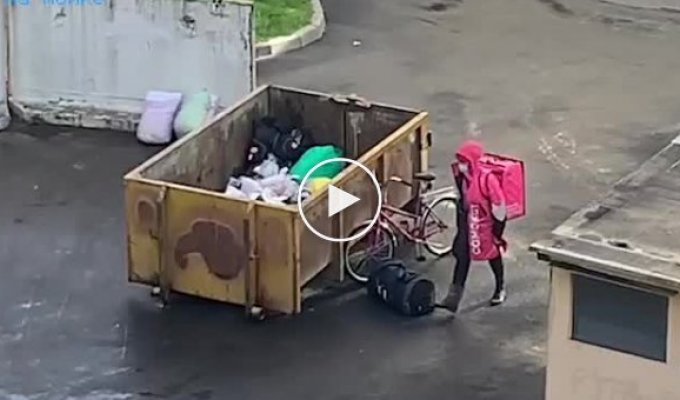 Доставщик еды роется в мусорном баке в Санкт-Петербурге
