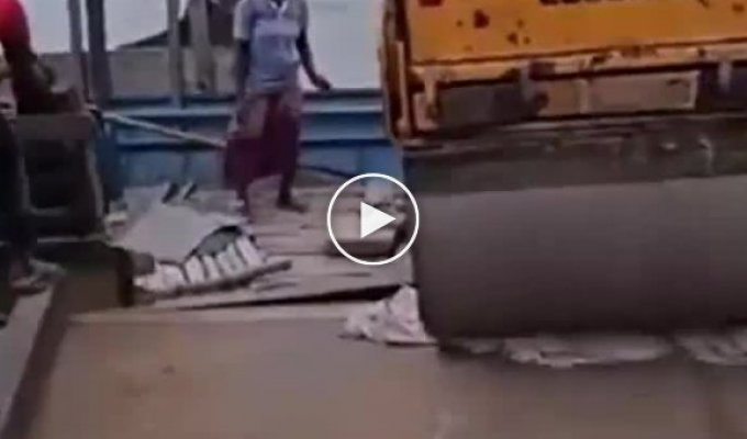 Workers sank a road roller while moving it onto a ship.
