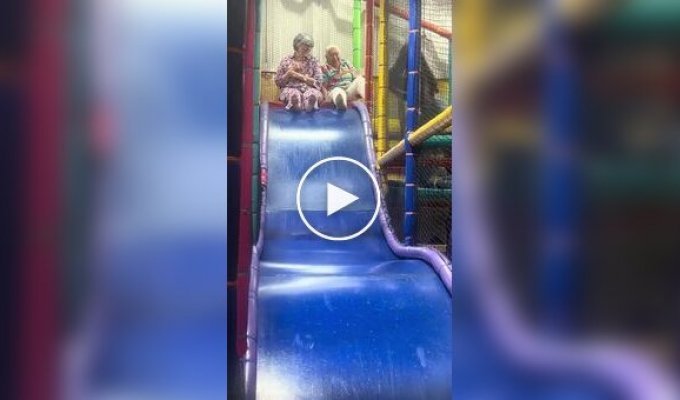 Cheerful grandmothers ride on a children's slide