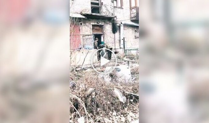 Three occupiers carry a washing machine along the street of occupied and destroyed Avdiivka